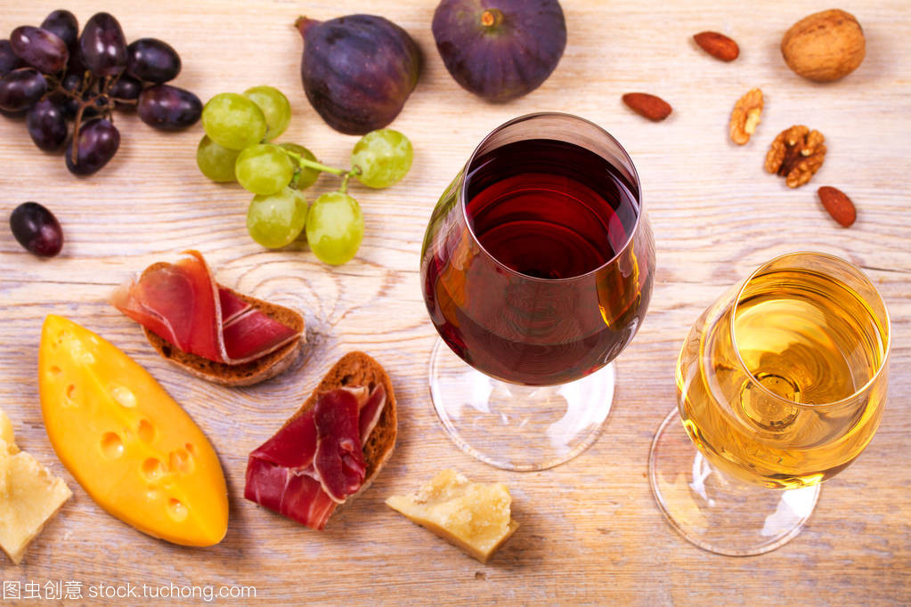 红色和白色奶酪、 火腿、 无花果和葡萄与葡萄酒杯。木制的桌子上的酒杯。葡萄酒的静物